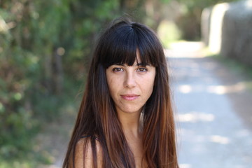 Portrait of a beautiful sexy brunette with bare shoulders on natural background