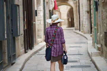 Turista con cappello e borsetta in una vecchia strada di paese