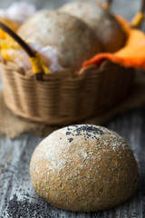 Fototapeta na wymiar Freshly baked homemade rye buns with poppy seeds in basket on wo