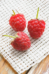 Red raspberry in front of white fabric on old vintage wooden tab