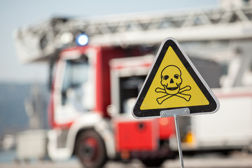 danger sign with skull and crossbones, fire truck on background