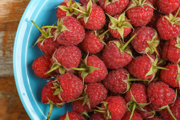 Red raspberry in blue dish on old vintage wooden table.
