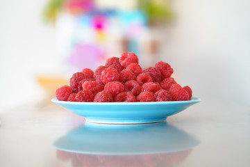 Red raspberry in blue dish on old vintage wooden table.