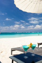 Blue Curacao cocktail with slice of pineapple on white beach