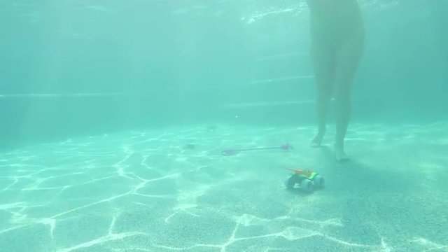 Woman stumbles on toys walking on the bottom of a pool