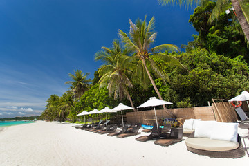 Sun umbrellas and beach chairs on tropical coast