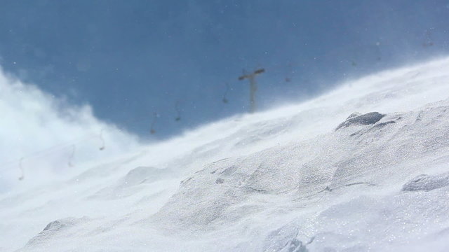 Strong wind carries snowflakes along the slope in the ski resort