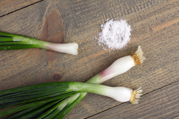 Two whole onions and bitten onion and salt on a brown wooden table