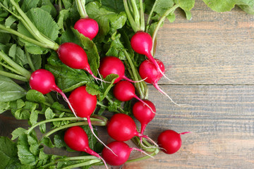 A lot of red radishes on a  brown wooden table