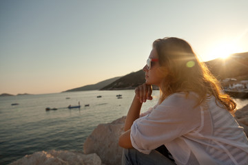 Fototapeta na wymiar Girl on the seashore watching the sunset