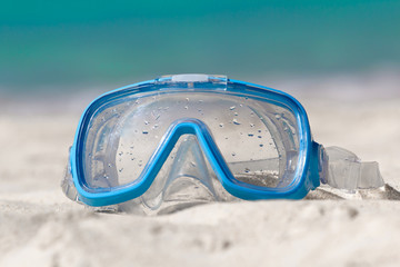 Swimming mask on white sand on tropical beach