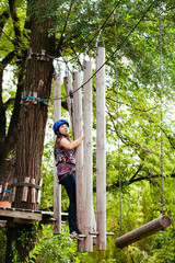 Naklejka na ściany i meble Adventure climbing high wire park - woman on course in mountain