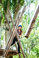 Tuinposter Adventure climbing high wire park - woman on course in mountain © davit85
