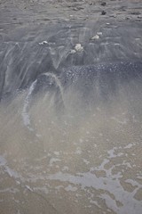 The merge of white and black sand on Indonesian beach shoreline