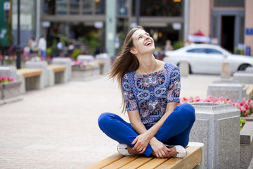 Happy Beautiful young woman sits on a bench