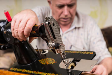 Senior Man Inspecting Old Fashioned Sewing Machine