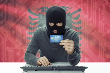 Dark-skinned hacker with flag on background holding credit card - Albania