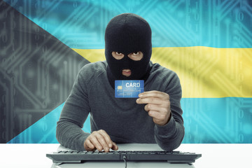 Dark-skinned hacker with flag on background holding credit card - Bahamas