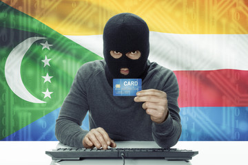Dark-skinned hacker with flag on background holding credit card - Comoros