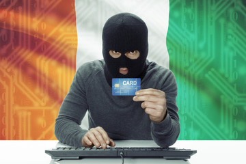 Dark-skinned hacker with flag on background holding credit card - Ivory Coast