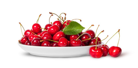 Obraz na płótnie Canvas Sweet cherries with leaf on white plate and three near