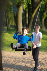 Fototapeta na wymiar Fun on the swing, the boys together on the playground 