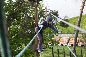 teenager climbing a rope park, boy climbing in adventure park 
