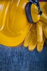 Working helmet safety earmuffs and yellow protective gloves on s