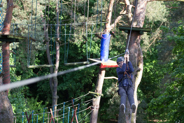 teenager climbing a rope park, boy climbing in adventure park 