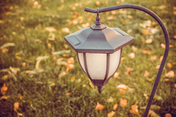 Graceful garden lantern with photocell on an autumn lawn. Ideas for decorating gardens and private estates