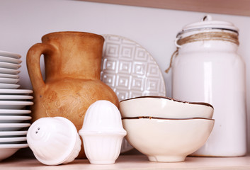 Kitchen utensils and tableware on wooden shelf