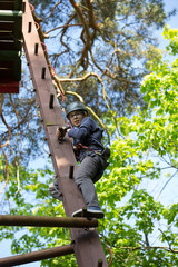 teenager climbing a rope park, boy climbing in adventure park 