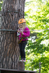 Naklejka na ściany i meble teenager climbing a rope park, Girl climbing in adventure park 