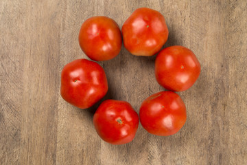 Some tomatoes over a wooden surface on a tomato field as backgro