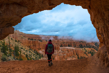 Girl Backpacker under Sandstone Arch Peek-a-boo Bryce