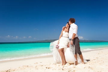 Fototapeta na wymiar Bride and groom having fun on beach