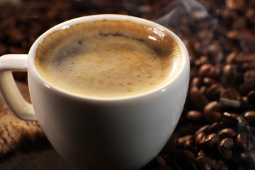 Cup of coffee with grains, closeup