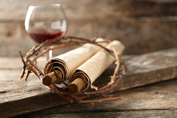 Crown of thorns, scroll and glass of wine on old wooden background