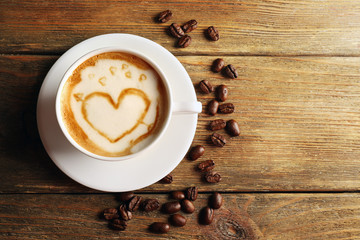 Cup of coffee latte art with grains on wooden background