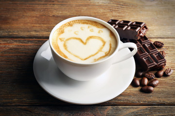 Cup of coffee latte art with grains and chocolate on wooden background