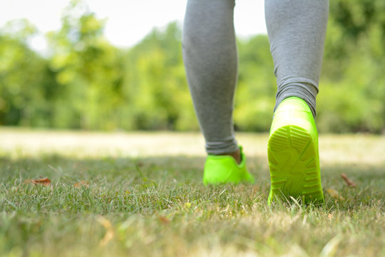 Runner woman feet running on grass closeup on shoe. Sports healthy lifestyle concept.