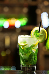 Glass of cocktail in bar on bright blurred background
