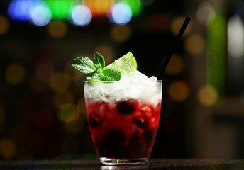 Glass of cocktail in bar on bright blurred background