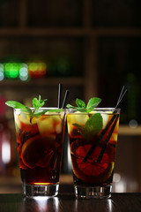 Glass of cocktail in bar on bright blurred background