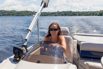 women driving a pontoon boat on a lake