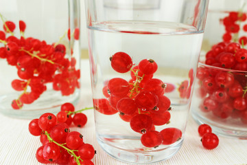 Johannisbeeren in Schale aus Glas auf Esstisch in Wasserglas und in Karaffe mit Wasser