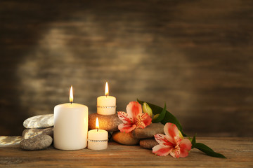 Beautiful composition with candles and spa stones on wooden background