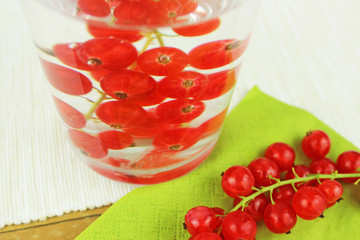 Johannisbeeren in Wasserglas und auf Esstisch