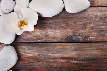 Spa stones and orchid flower on wooden background