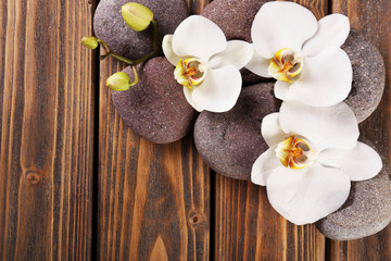 Fototapeta na wymiar Spa stones and orchid flower on wooden background